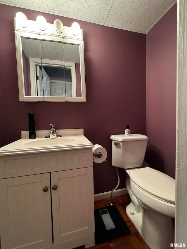 bathroom featuring hardwood / wood-style floors, vanity, a drop ceiling, and toilet