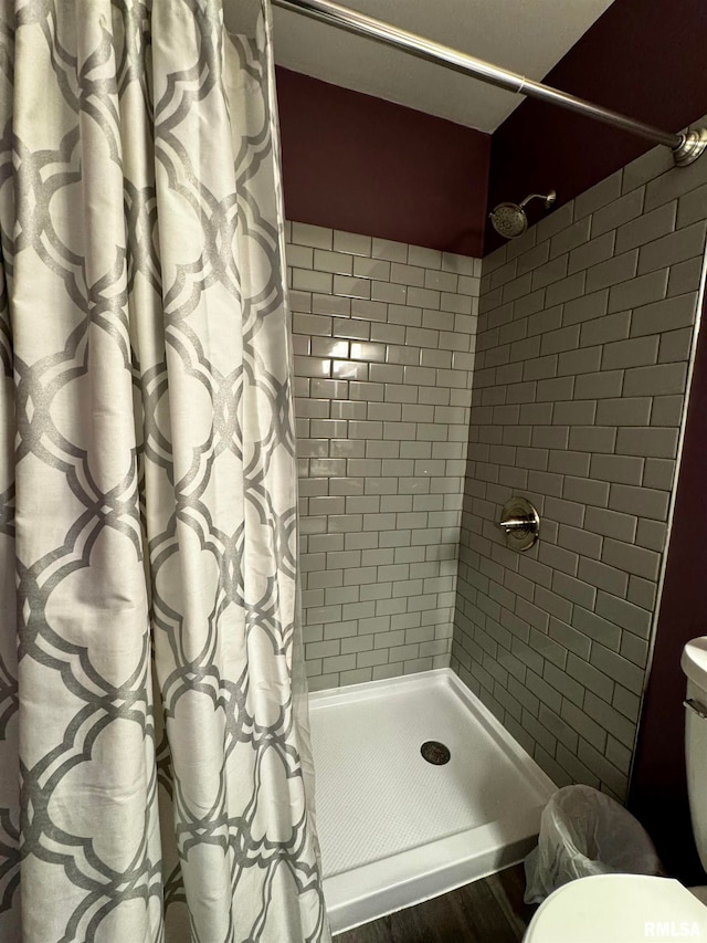 bathroom with toilet, walk in shower, and wood-type flooring