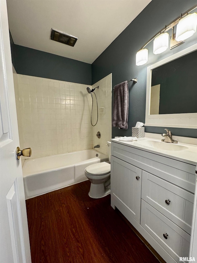 full bathroom with tiled shower / bath, vanity, hardwood / wood-style flooring, and toilet