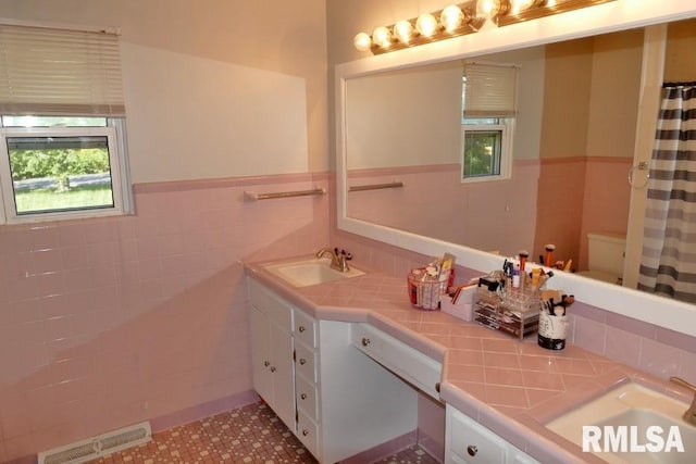 bathroom featuring tile walls, vanity, toilet, and tile patterned flooring