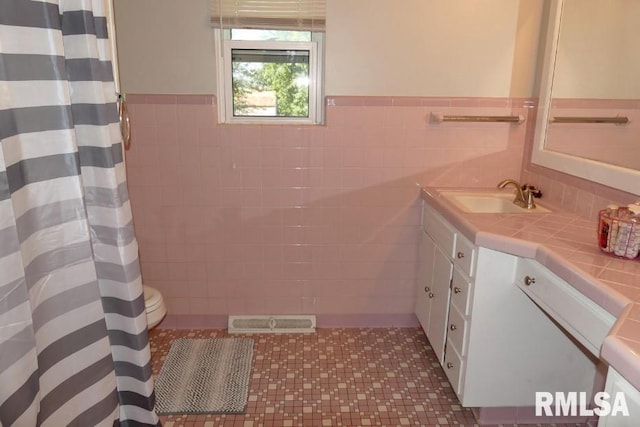 bathroom featuring vanity, toilet, and tile walls