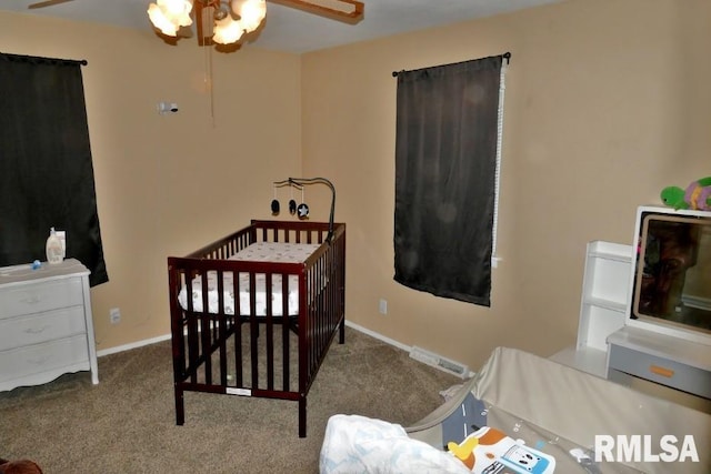 bedroom featuring a nursery area, carpet floors, and ceiling fan