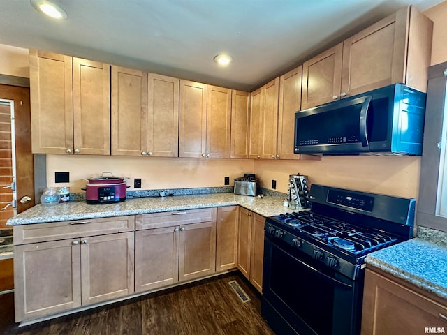 kitchen with black gas range, dark wood-type flooring, light brown cabinets, and light stone countertops