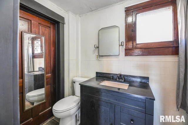 bathroom with vanity, toilet, and tile walls