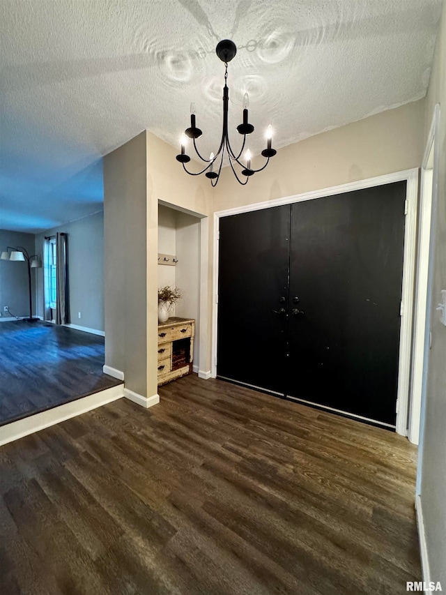 unfurnished dining area featuring a textured ceiling, an inviting chandelier, and dark hardwood / wood-style floors