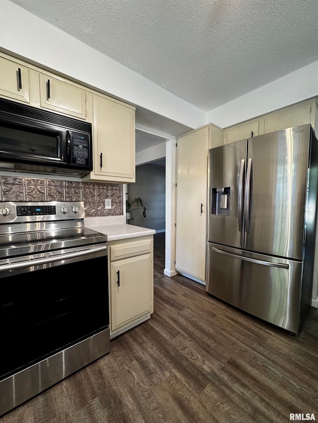 kitchen with cream cabinets, dark wood-type flooring, stainless steel appliances, a textured ceiling, and tasteful backsplash