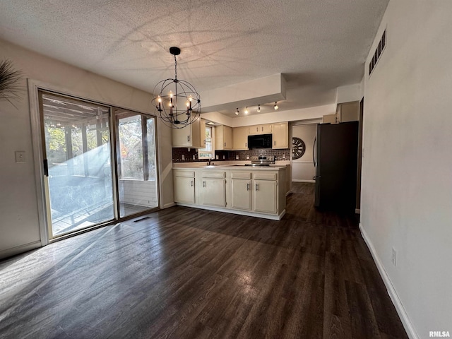 kitchen featuring tasteful backsplash, appliances with stainless steel finishes, a textured ceiling, dark wood-type flooring, and a notable chandelier