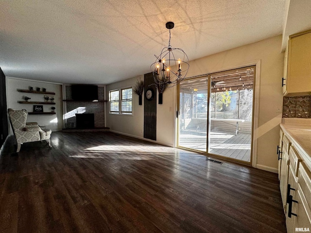 dining area featuring an inviting chandelier, dark hardwood / wood-style floors, a textured ceiling, and a brick fireplace