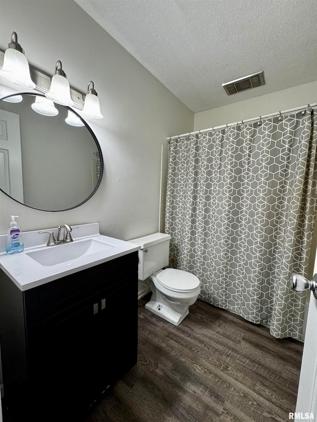 bathroom with hardwood / wood-style floors, a textured ceiling, toilet, vanity, and a shower with curtain