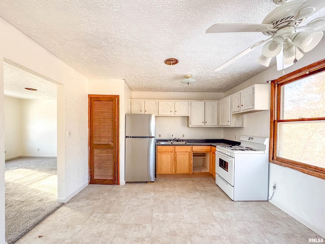 kitchen with gas range gas stove, stainless steel fridge, ceiling fan, light colored carpet, and sink