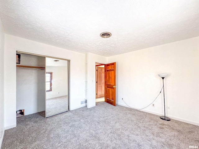 unfurnished bedroom with carpet, a closet, and a textured ceiling