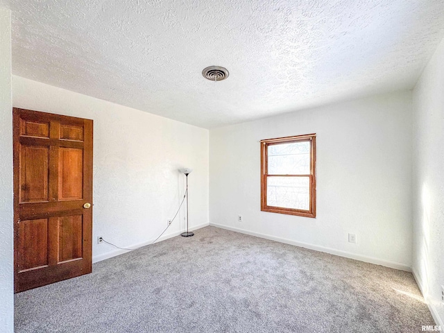 carpeted empty room with a textured ceiling