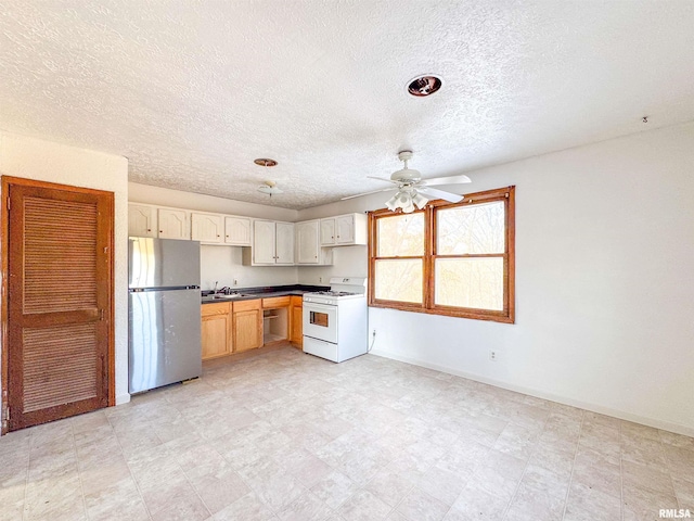 kitchen featuring ceiling fan, sink, stainless steel fridge, and gas range gas stove