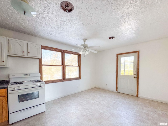 kitchen featuring ceiling fan, white cabinets, and gas range gas stove