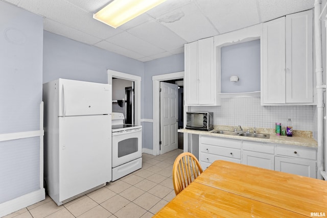 kitchen featuring white appliances, sink, white cabinets, decorative backsplash, and light tile patterned floors