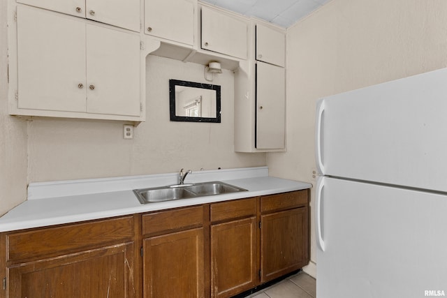 kitchen with white fridge, light tile patterned floors, and sink