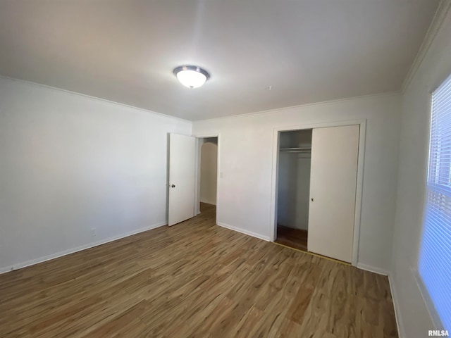 unfurnished bedroom with a closet, ornamental molding, and dark hardwood / wood-style floors