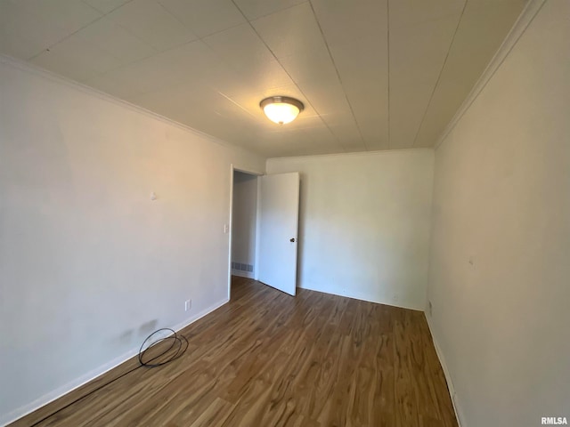 empty room with dark wood-type flooring and crown molding