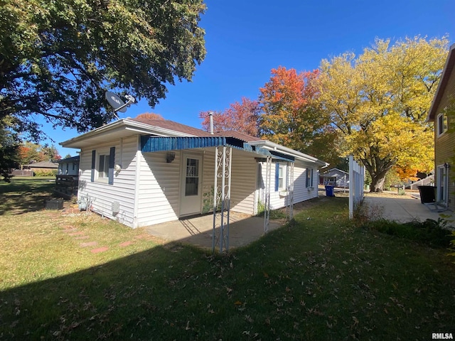 view of side of home with a patio and a lawn