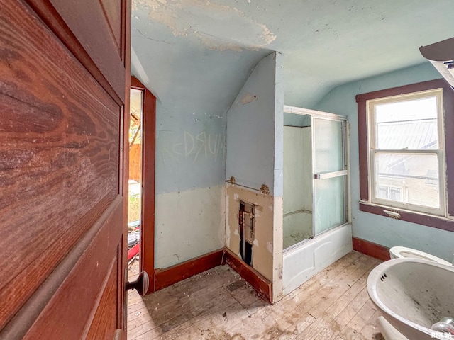 bathroom featuring shower / bath combination with glass door, toilet, hardwood / wood-style flooring, and lofted ceiling