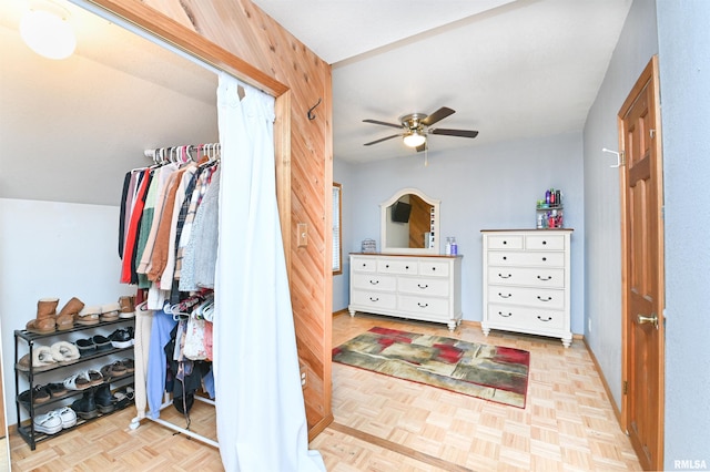 bedroom featuring wood walls, light parquet flooring, and ceiling fan