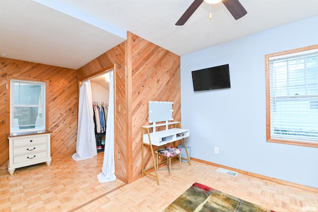 bedroom with light parquet flooring, wooden walls, and ceiling fan