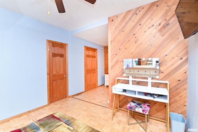 bedroom featuring parquet floors, wooden walls, and ceiling fan