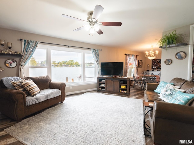 living room featuring dark wood-type flooring and ceiling fan with notable chandelier