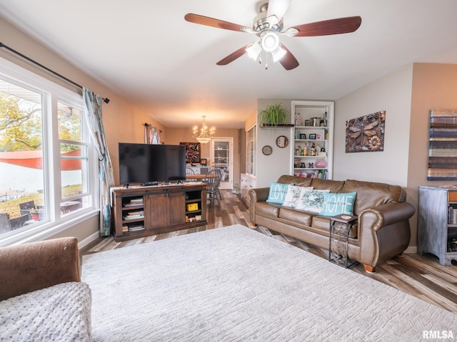 living room with hardwood / wood-style flooring and ceiling fan with notable chandelier