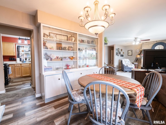 dining area with ceiling fan with notable chandelier and dark hardwood / wood-style flooring