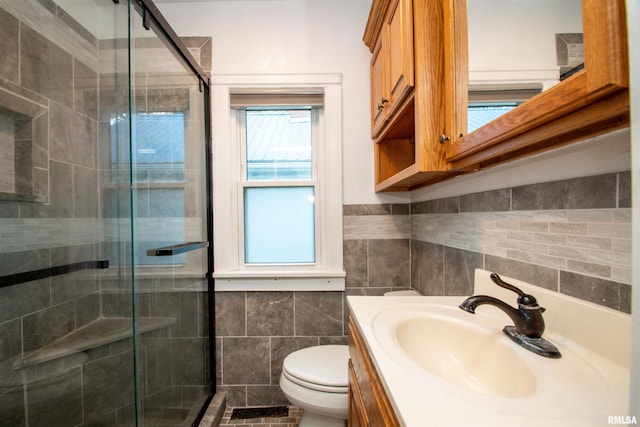 bathroom featuring a shower with door, vanity, toilet, and tile walls