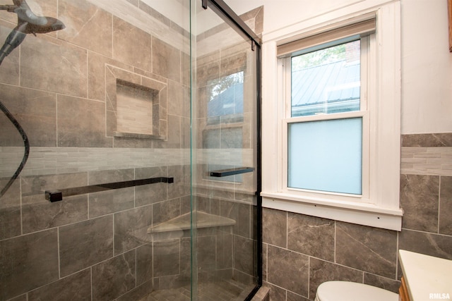 bathroom with tile walls, vanity, toilet, and walk in shower