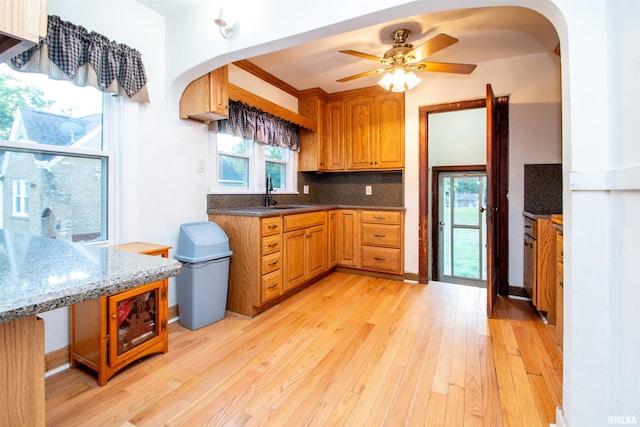 kitchen with tasteful backsplash, sink, light wood-type flooring, and ceiling fan