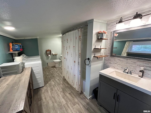 full bathroom featuring wood-type flooring, washing machine and clothes dryer, toilet, vanity, and shower / tub combo with curtain