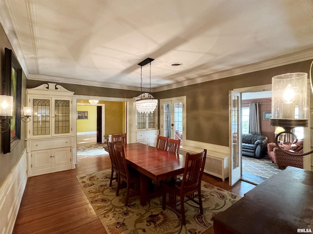 dining area featuring french doors, crown molding, wood-type flooring, and a chandelier