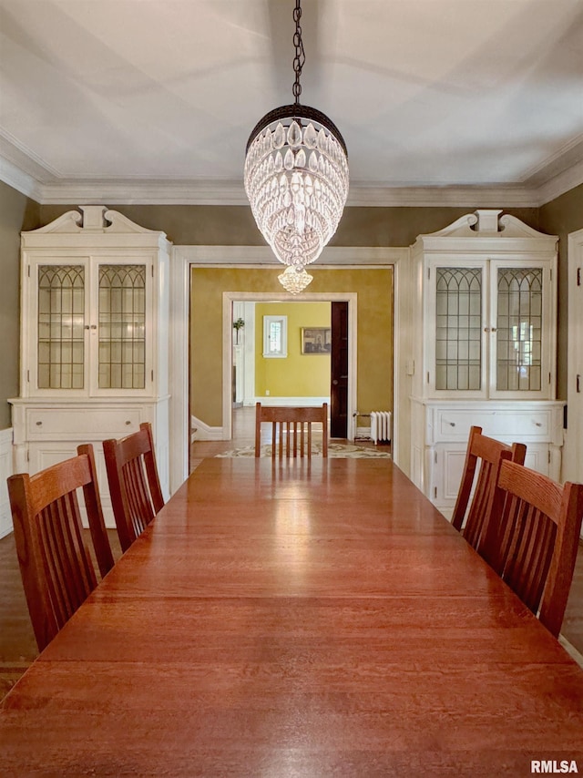 dining space with hardwood / wood-style floors, ornamental molding, a chandelier, and radiator heating unit