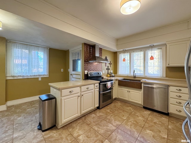 kitchen with wall chimney range hood, kitchen peninsula, appliances with stainless steel finishes, and a wealth of natural light