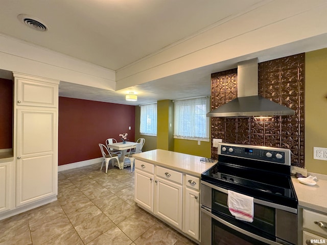 kitchen featuring stainless steel range with electric stovetop, wall chimney exhaust hood, and white cabinets