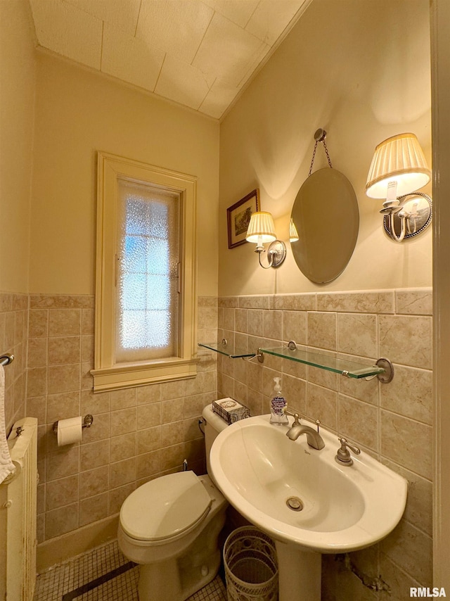 bathroom with toilet, sink, tile walls, and tile patterned flooring