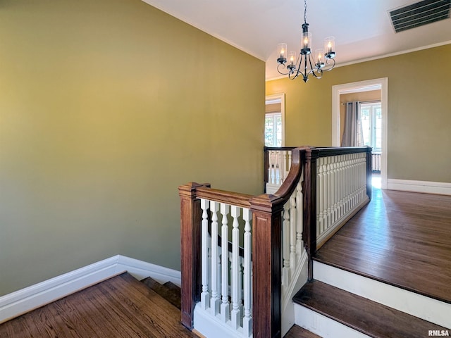 stairway with hardwood / wood-style floors and a chandelier