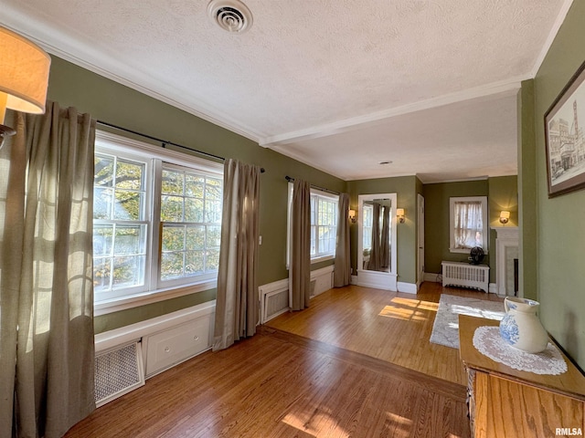 doorway to outside with a textured ceiling, wood-type flooring, and radiator