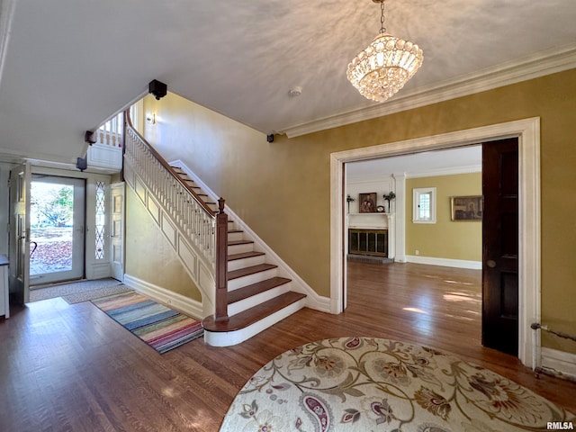 foyer entrance with ornamental molding, hardwood / wood-style flooring, and a chandelier