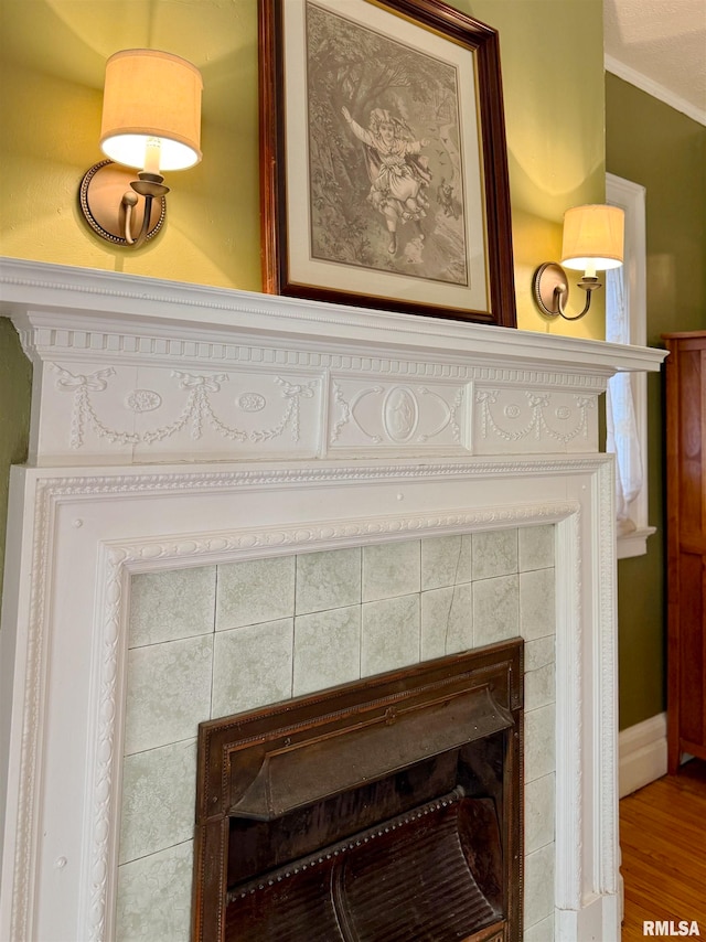 interior details featuring crown molding, hardwood / wood-style flooring, and a tile fireplace