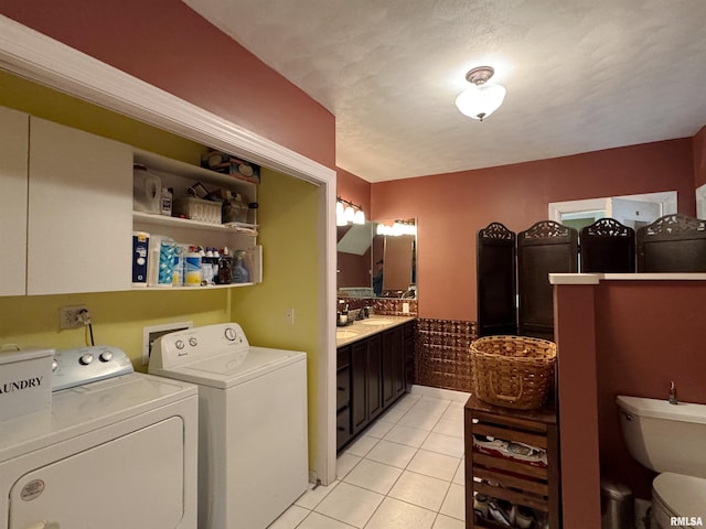 washroom featuring a textured ceiling, light tile patterned flooring, sink, and separate washer and dryer