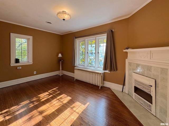 unfurnished living room with light hardwood / wood-style floors, crown molding, radiator heating unit, and a wealth of natural light