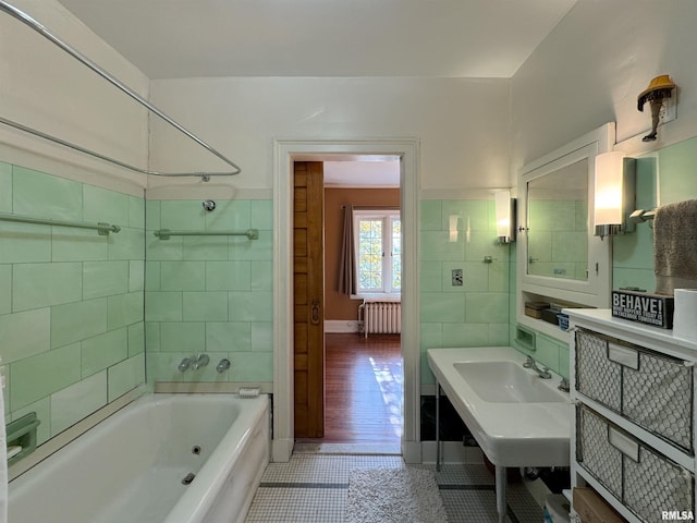 bathroom with wood-type flooring, sink, tile walls, radiator heating unit, and a bath