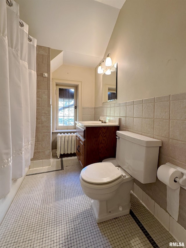 bathroom with tile patterned floors, toilet, radiator, tile walls, and vanity