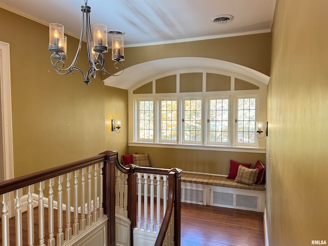 staircase featuring hardwood / wood-style flooring, ornamental molding, and an inviting chandelier