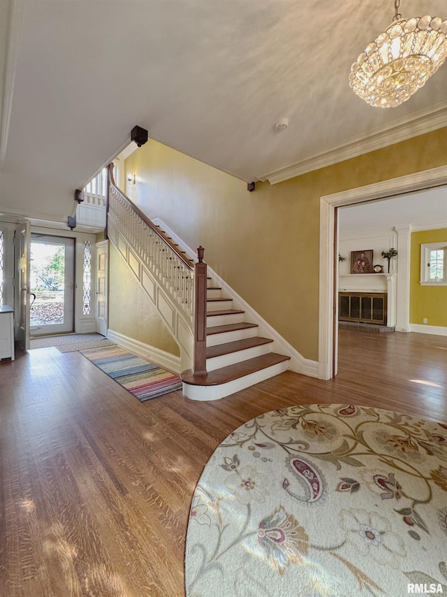 foyer with hardwood / wood-style floors, a chandelier, and crown molding