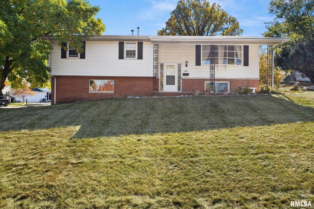 bi-level home with a front lawn and brick siding